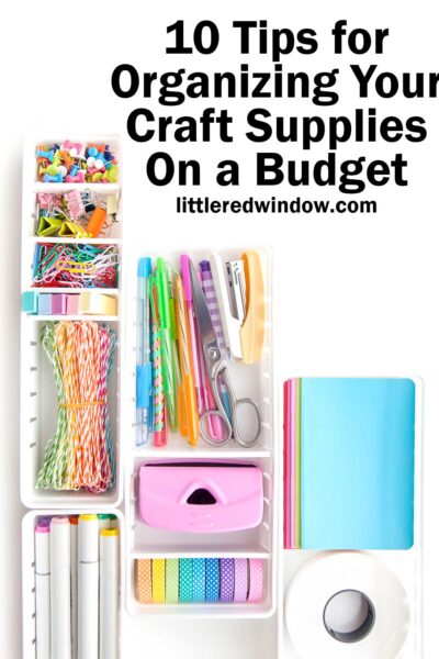 Top view of a white rectangular boxes filled with rainbow colored organized craft supplies on a white background