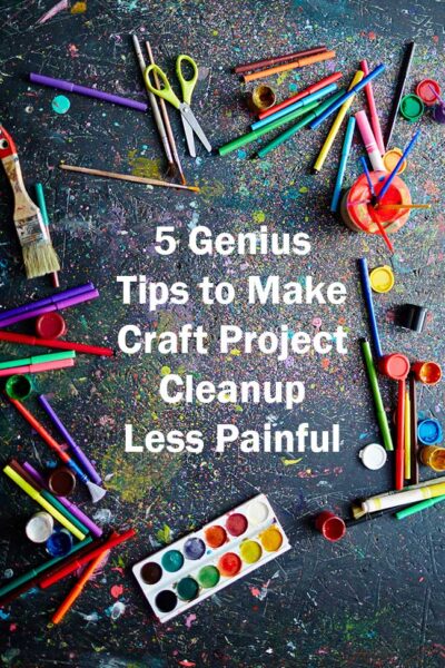 colorful paintbrushes markers pens and paint scattered on a dark gray messy background