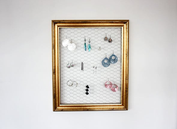 Picture frame filled with chicken wire with earrings hanging on it