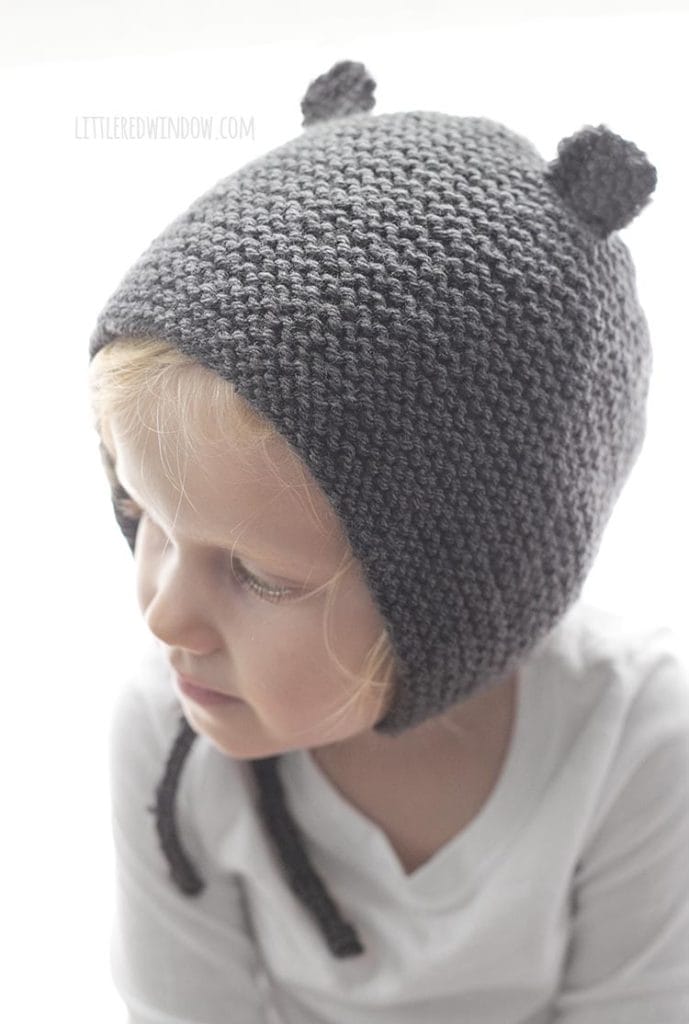 little girl wearing gray bear ear knit bonnet and looking off to the left