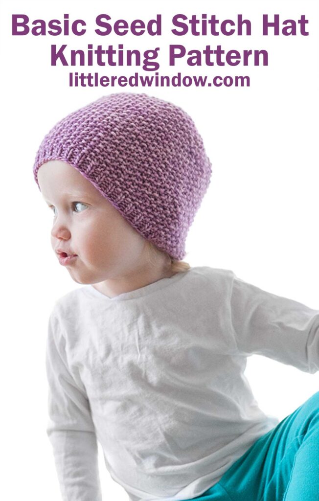 toddler in white shirt and teal pants leaning off to the left and wearing an orchid purple knit hat with small ribbed brim an the rest knit in seed stitch knitting pattern