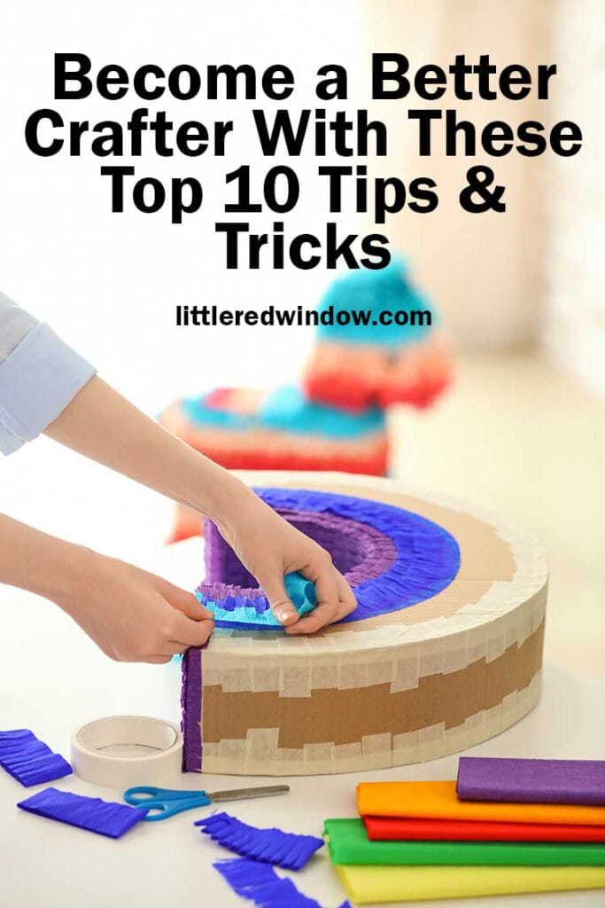 hands making add strips of paper to an arch shaped cardboard object on a wood table