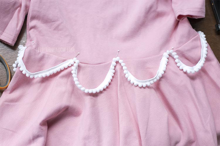 pink dress with pink pom pom trim swagged around the waist to look like frosting on a birthday cake costume