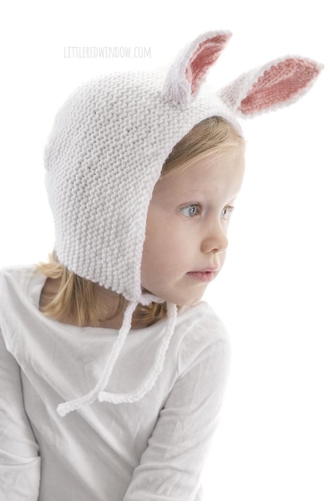 little girl wearing white knit bonnet with bunny ears and looking off to the right