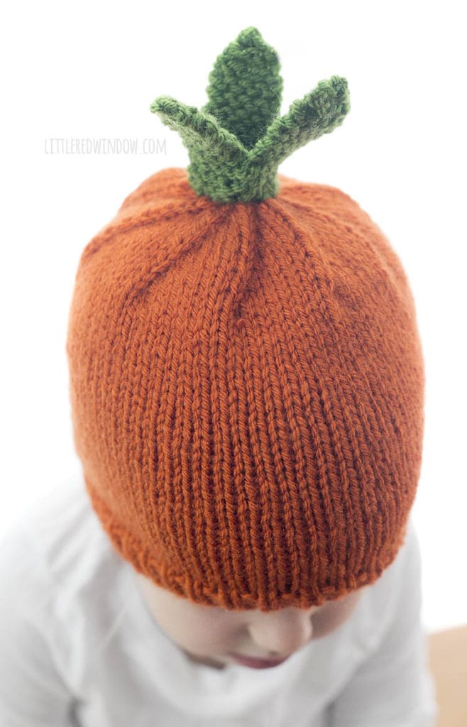 top view of orange and green knit carrot hat