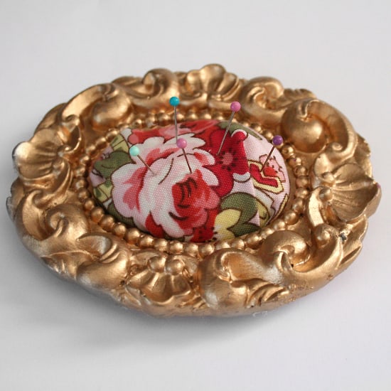 gold frame filled with fabric pincushion