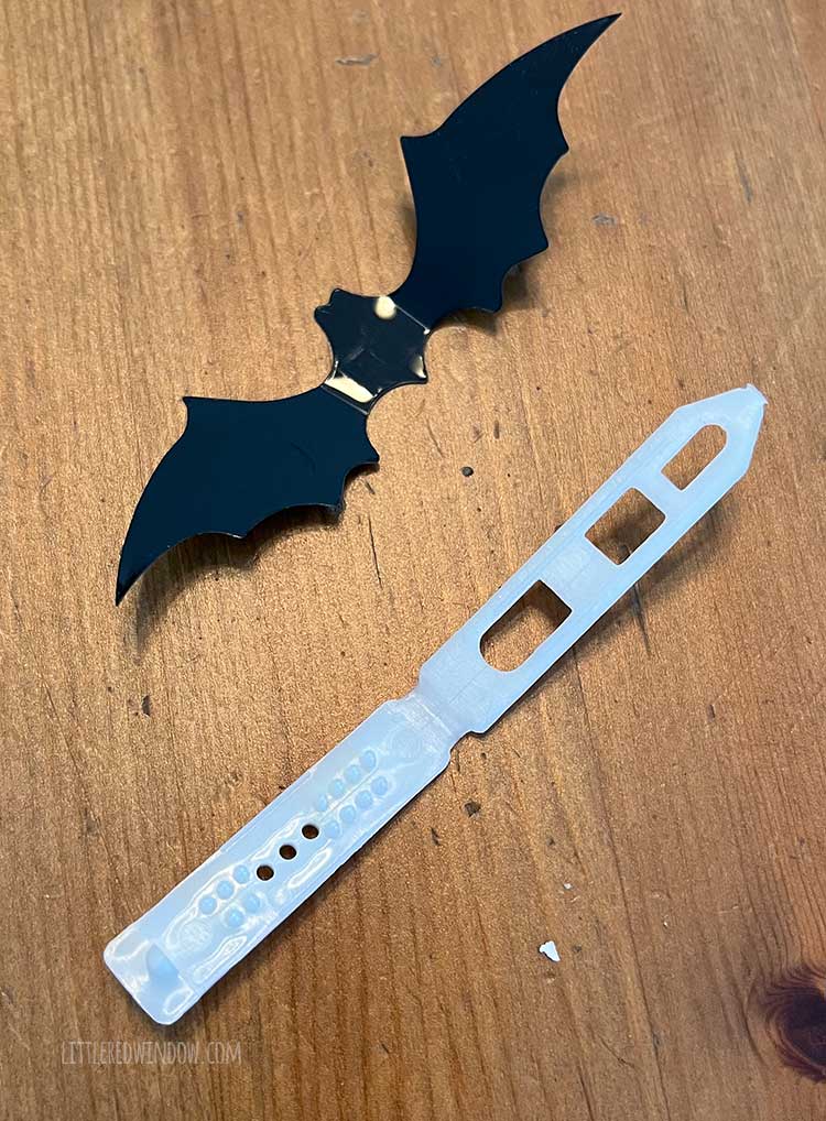 small black bat shape and white blank barette on a wood tabletop