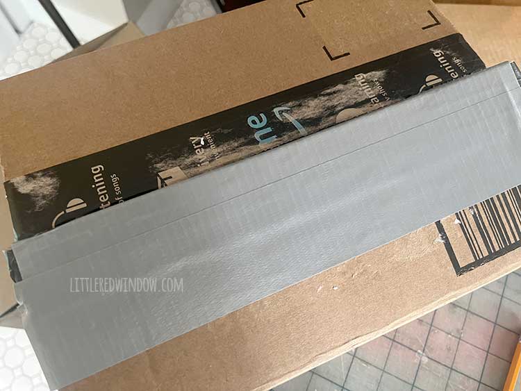 image showing the edge of one flap of a cardboard box covered with silver duct tape