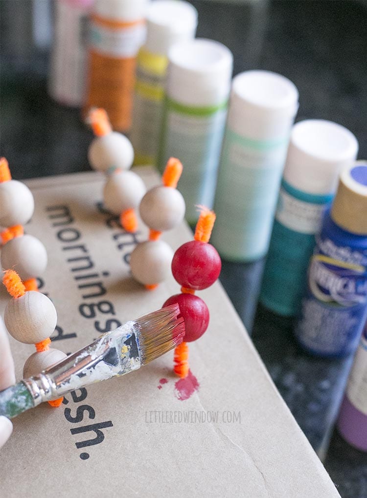 Paint wooden beads with acrylic craft paint in rainbow colors to make a DIY rainbow wall hanging!