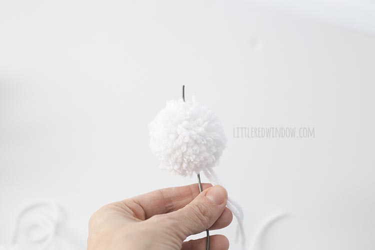 Add a pom pom to the end of your DIY rainbow wall hanging!