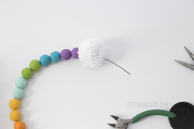 Add a pom pom to the end of your DIY rainbow wall hanging!