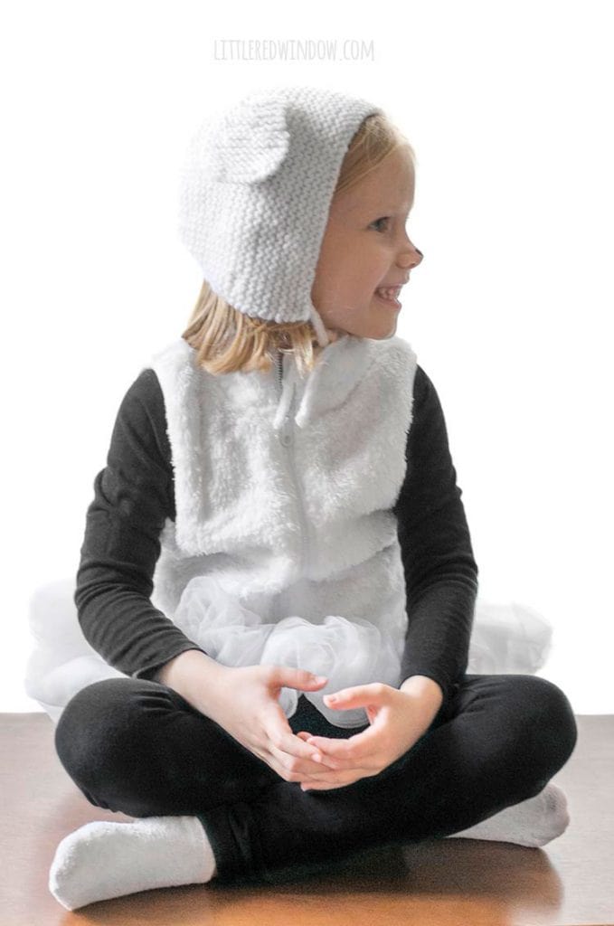 little girl wearing sheep ears bonnet and easy diy sheep costume smiling and looking off to the right