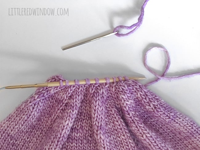 Easy Knit Flat Baby Hat Seam technique showing the last 9 stitches on one needle with the tail threaded on a yarn needle