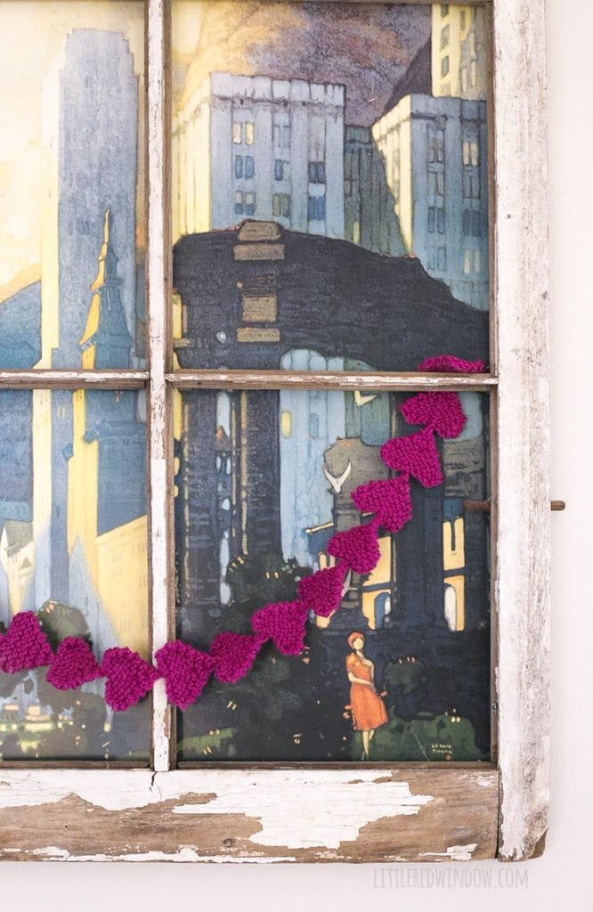Easy knit heart garland strung over a vintage window