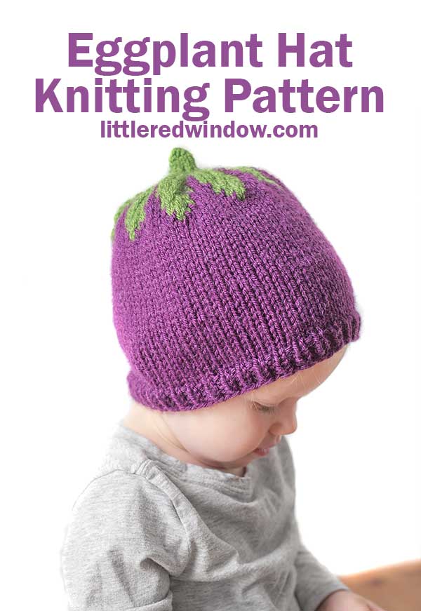 left side view of baby in gray shirt wearing a purple knit hat with green leaves on top that looks like an eggplant  in front of a white background 