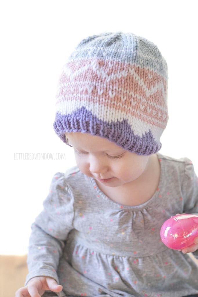 baby wearing knit easter egg hat and holding one pink easter egg