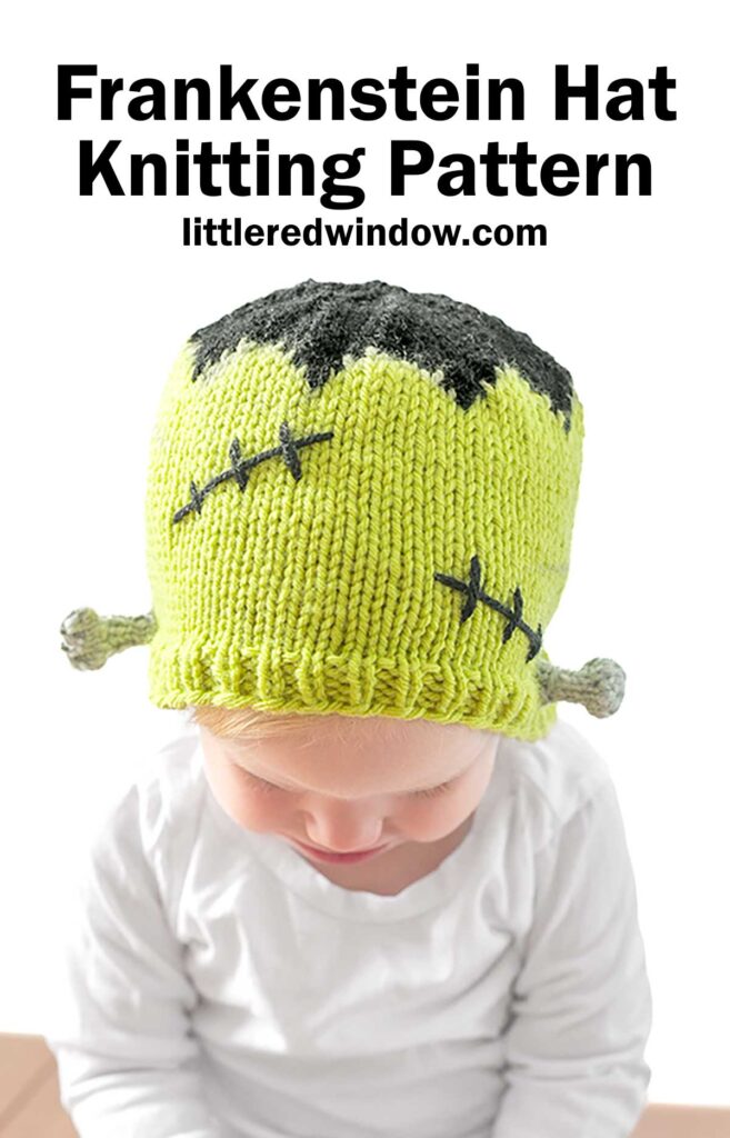 A baby wearing a green knitted Frankenstein Hat designed to resemble Frankenstein's monster, with black hair-like detail at the top and stitched patterns on the sides. The hat has small protrusions on each side, mimicking bolts. The text at the top reads,