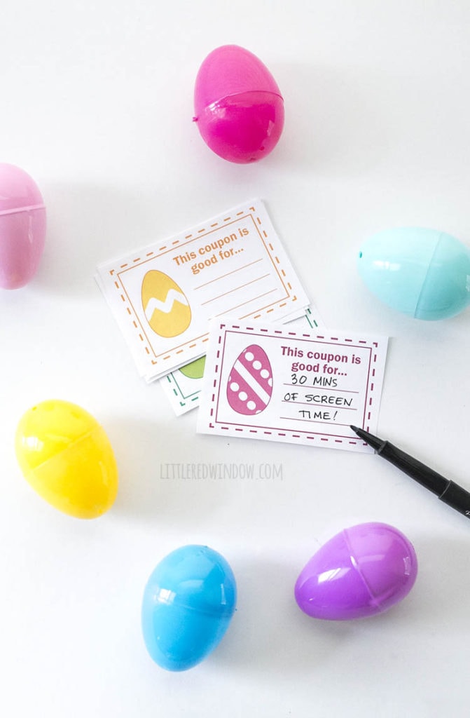 Fill in the blank easter egg coupons next to a black pen that has written 30 mins of screen time and surrounded by plastic easter eggs on a white background