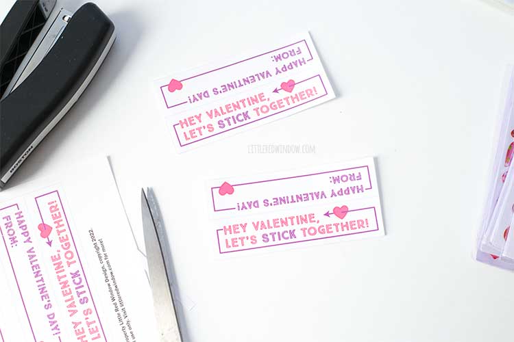 two printable sticker valentines cut out and laying on a white background next to a pair of scissors