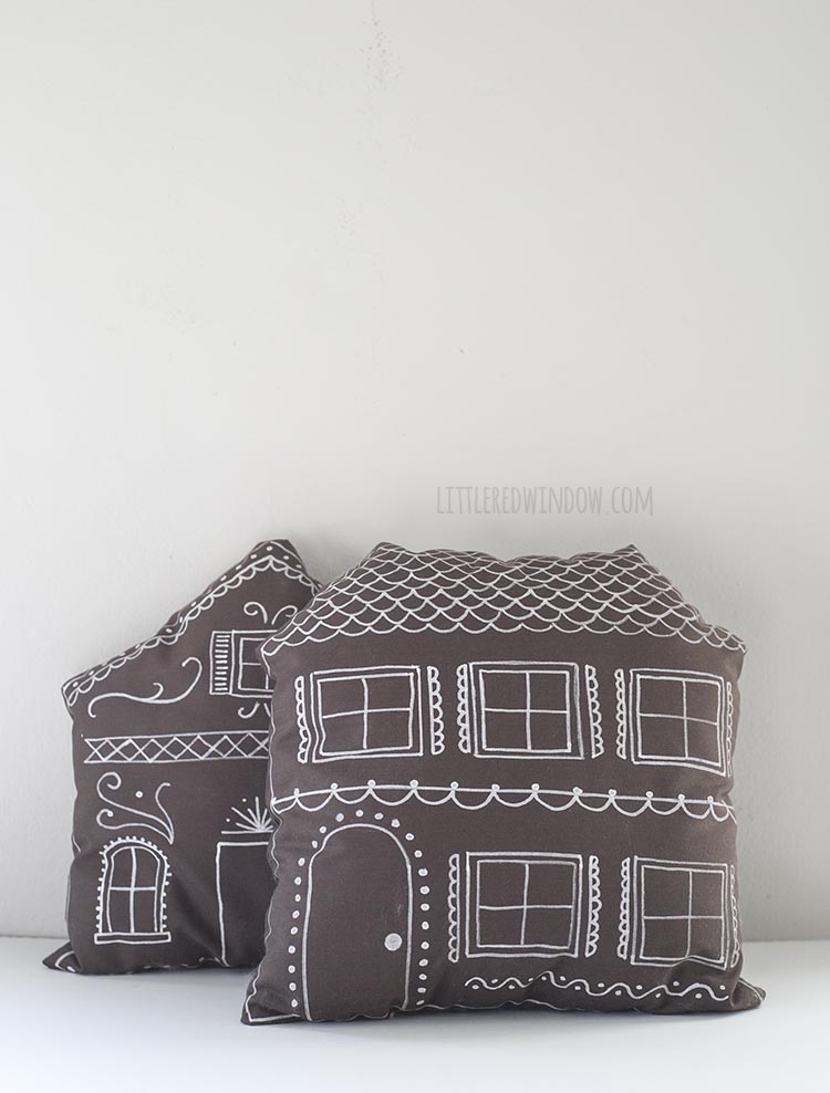 two brown pillows decorated like gingerbread houses leaning on a wall