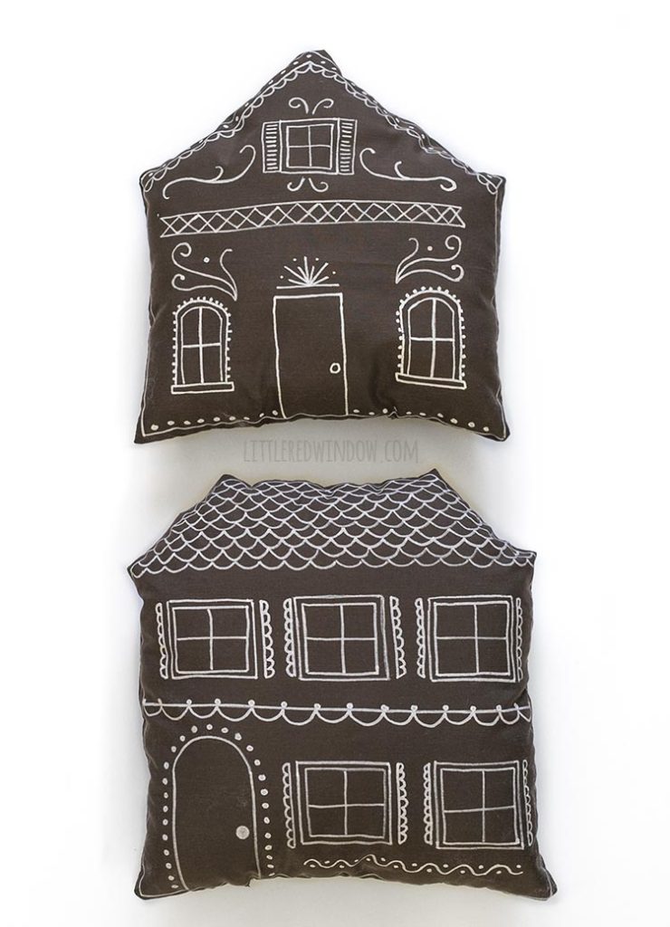 two brown pillows shaped and decorated like gingerbread houses on a white background
