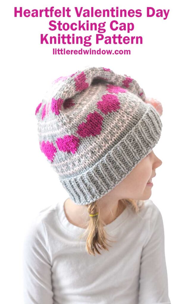 Young girl wearing a gray and pink knit stocking cap with heart patterns, looking to the side. Text reads:
