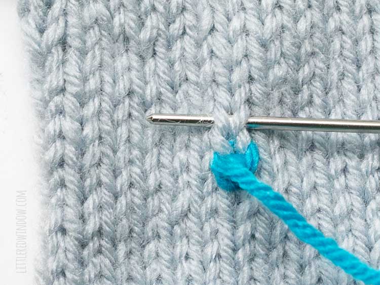 yarn needle inserted above one duplicate stitch showing the second step of the second stitch