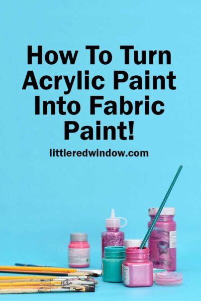 small jars of purple and pink paint with paintbrushes in front of a medium blue backgrounf