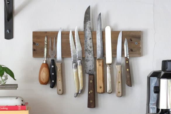 Piece of wood with hiddne magnet holding a variety of knives onto a wall