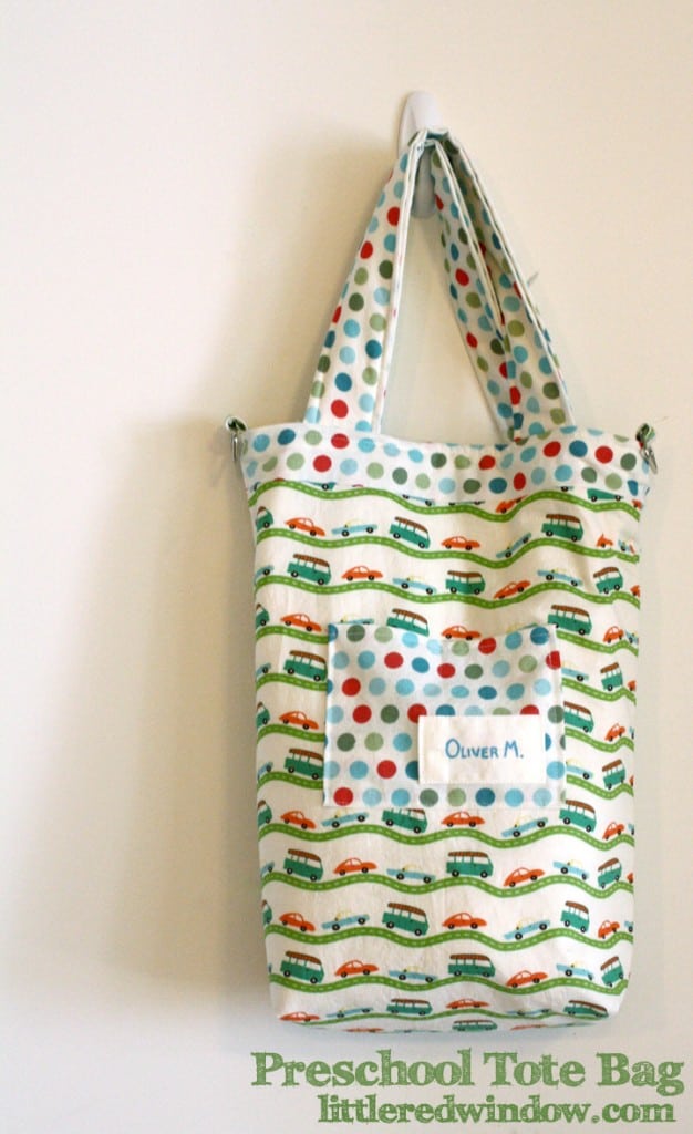 Handmade tote back with red and blue and green car and bus fabric in front of a white wall