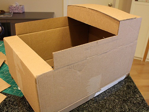 The top flaps of a cardboard box cut to make the shape of Thomas the Train, this time with a roof added to the back