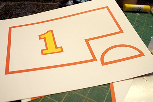 Piece of paper with decorative red rectangle and half circle and yellow number 1 to cut out and paste to the side of the train