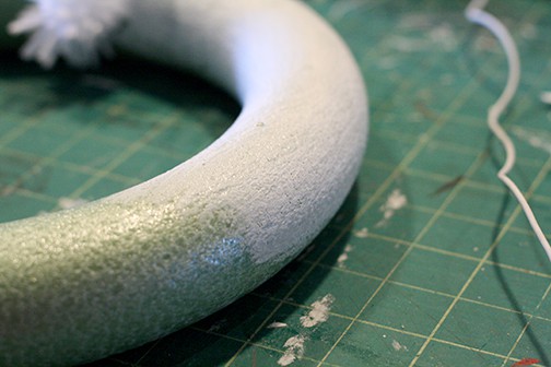 Green styrofoam wreath form halfway painted white