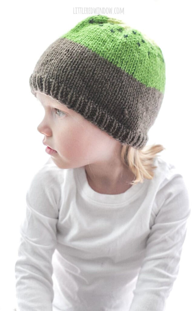 girl wearing knit kiwi hat for babies and looking off to the left