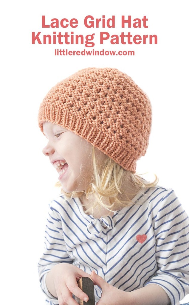 laughing girl in white shirt with navy stripes and a coral colored knit lace grid hat looking off to the left