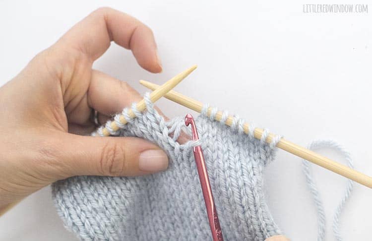 Insert a crochet hook through the dropped knit stitch