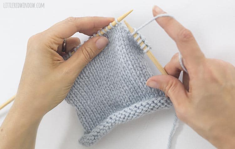 To knit a knit stitch, hold the yarn behind the work