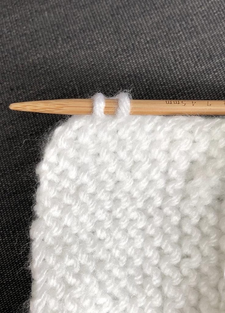 corner of garter stitch with one knitting needle picking up two stitches