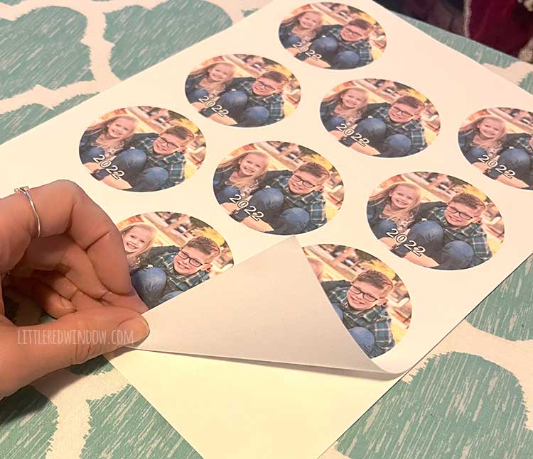 hand peeling the backing of a sheet of printable fabric with circular pictures of children on it