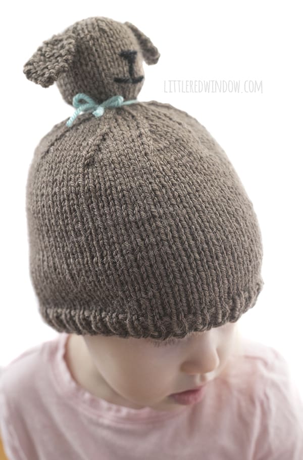 Little girl loves showing off the Puppy Dog Pom Pom Pet Hat knitting pattern. This cute little guy even has an adorable puppy nose and cute floppy ears!