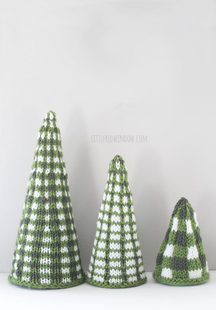 Three green and white plaid knit Christmas tree shapes in a line from large to small