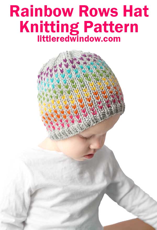 A child wears a knitted hat adorned with rainbow colors and a gray brim, perfectly capturing the charm of the