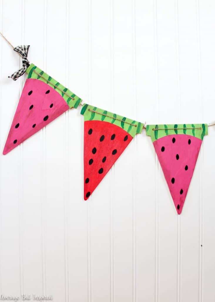 Cute triangle bunting painted to look like watermelon slices hanging in front of a white wall