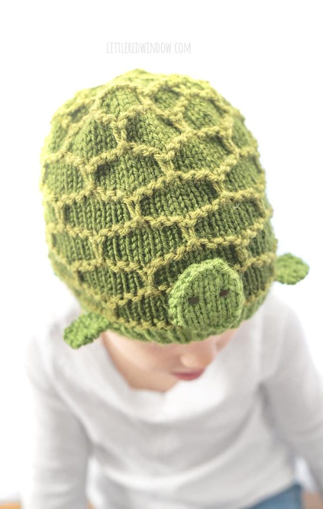 closeup of green turtle hat knitting pattern with hexagon pattern shell feet and a little face