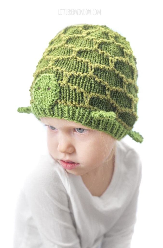 little girl in green turtle hat looking up and to the left
