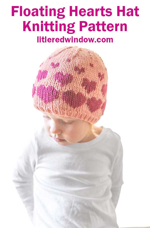 A child in a pink knitted hat adorned with heart patterns gazes downward. The text at the top reads,