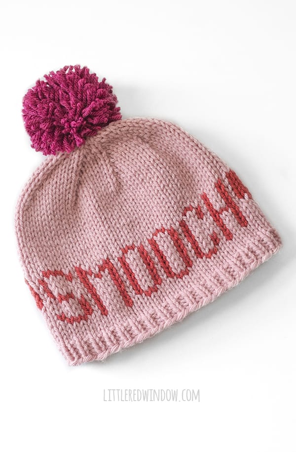 light pink knit love notes hat with magenta pom pom and the word SMOOCH in red on a white background